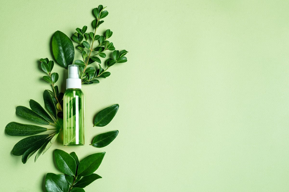 Producto de limpieza sobre hojas verdes con fondo verde